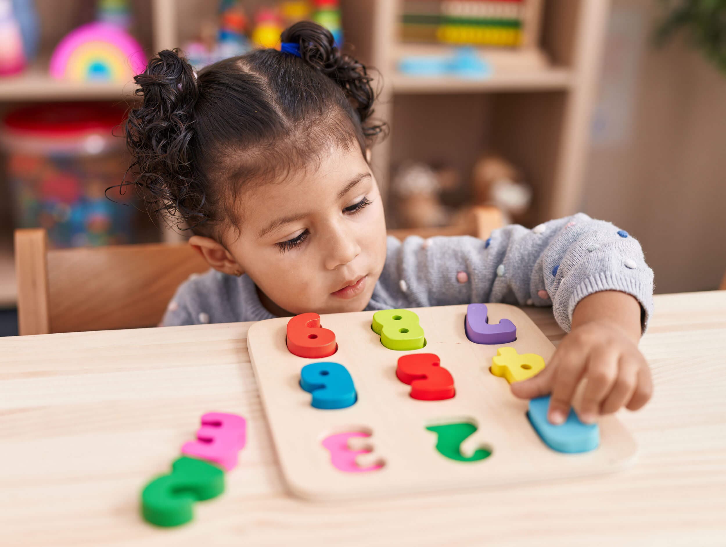 A young child fitting colorful wooden number pieces into a puzzle board
